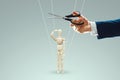 A man`s hand cuts the threads between the puppeteer and the puppet with scissors. The concept of liberation from slavery, freedom Royalty Free Stock Photo