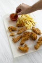 Man`s hand dipping chicken strips into sauce, side view