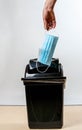 Man`s hand drops medical bask into bin. White background