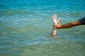 A man`s hand drowns in water calling for help, man helps rescue, against the background of the sea