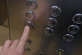 The man`s hand in the elevator presses the first floor button. Metal surface, round buttons with numbers. Royalty Free Stock Photo