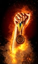 Man`s hand in a fire is holding up gold medal. Winner in a competition. Royalty Free Stock Photo