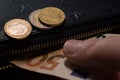 Man`s hand gets euro money out from leather wallet with coins on it