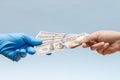 Man`s hand giving money dollars to hand in blue surgical glove, nurse or doctor. Corruption in medicine field