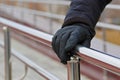 Man`s hand in glove holding hand rail while walking down stairs Royalty Free Stock Photo