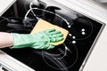 Man`s hand in green glove cleaning cooker at home kitchen Royalty Free Stock Photo