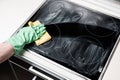 Man`s hand in green glove cleaning cooker at home kitchen Royalty Free Stock Photo