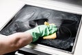 Man`s hand in green glove cleaning cooker at home kitchen Royalty Free Stock Photo