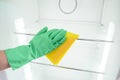 Man`s hand in green glove cleaning empty refrigerator Royalty Free Stock Photo