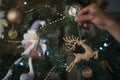 Man`s hand hanging a golden shiny deer on a decorated christmas tree. Royalty Free Stock Photo