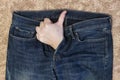 A man`s hand, with his thumb raised, protrudes from the fly of his jeans.