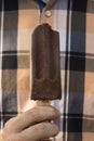 Man's hand hoding a bitten chocolate ice-lolly
