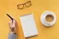 Man`s hand hoding pen near blank notepad on the table with coffee and glasses