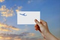 Man's hand holding airplane symbol paper in sky. Concept of journey, travel, dream, freedom.