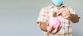 A man`s hand holding a bitcoin coin to drop pink pig piggy bank. the concept for saving money in form of bitcoins giving higher Royalty Free Stock Photo