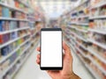 Man`s hand holding blank white screen mobile phone on blurred supermarket background