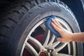 Man's hand holding a blue fabric cleaning car tires and wheels Royalty Free Stock Photo