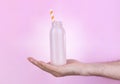 Man's hand holding a bottle of milk on a pink background. Royalty Free Stock Photo