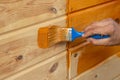 Man`s Hand holding a brush applying varnish paint on a wooden surface. Brush on wooden background. Board half painted Royalty Free Stock Photo