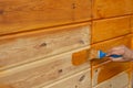 Man`s Hand holding a brush applying varnish paint on a wooden surface. Brush on wooden background. Board half painted Royalty Free Stock Photo