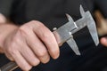 A man`s hand holding a caliper. An adult man with a high-precision metal instrument for measuring the external and internal Royalty Free Stock Photo