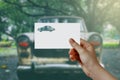 Man's hand holding car symbol paper on road. Concept of journey, travel, dream, freedom.