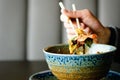 Man`s hand holding chopsticks over a plate of Japanese, thai, chinese meal - rice, mushroom, vegetables. Cafe Royalty Free Stock Photo