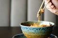 Man`s hand holding chopsticks over a plate of Japanese, thai, chinese meal - rice, mushroom, vegetables. Cafe Royalty Free Stock Photo