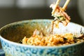 Man`s hand holding chopsticks over a plate of Japanese, thai, chinese meal - rice, mushroom, vegetables. Cafe Royalty Free Stock Photo