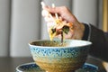 Man`s hand holding chopsticks over a plate of Japanese, thai, chinese meal - rice, mushroom, vegetables. Cafe Royalty Free Stock Photo