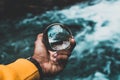 Man's hand holding a crystal ball reflecting nature