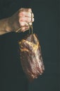 Man` s hand holding cut of cured pork meat Royalty Free Stock Photo