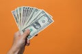 Man's hand holding dollar bills with copy space on orange background Royalty Free Stock Photo
