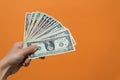 Man's hand holding dollar bills with copy space on orange background Royalty Free Stock Photo