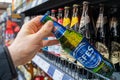 Man`s hand is holding Efes beer bottle from supermarket shelf. Various bottles of beer on shelf in store. Minsk, Belarus, 2022