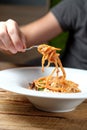 Man`s hand holding a fork with spaghetti over a plate. Royalty Free Stock Photo