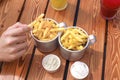 Man`s hand holding french fries. Top view of table with lemonades, fast food, sauces, french fries
