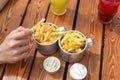 Man`s hand holding french fries. Top view of table with lemonades, fast food, sauces, french fries.Selective focus.