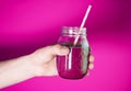 Man`s hand holding a glass jar with berry smoothie on the white wall background. Royalty Free Stock Photo