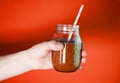 Man`s hand holding a glass jar with berry smoothie on the white wall background. Royalty Free Stock Photo