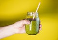 Man`s hand holding a glass jar with berry smoothie on the white wall background. Royalty Free Stock Photo