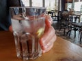 Man`s hand holding glass with water, ice cubes, lemon and straw