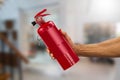 Man`s hand holding handy fire extinguisher on blurred house background Royalty Free Stock Photo