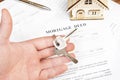 Man's hand holding keys of house over mortgage deed Royalty Free Stock Photo