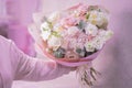 A man`s hand is holding a lush beautiful bouquet of light pink, white cute delicate small roses of different sizes, flowers