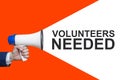 Man`s Hand Holding Megaphone With Speech Bubble VOLUNTEERS NEEDED. Announcement And Advertising