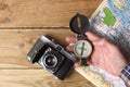 Man`s hand holding an orientation compass on a wooden table with a map and copy space for your text Royalty Free Stock Photo