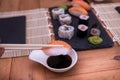 Man`s hand holding a pair of chopsticks and a Nigiri sushi over the soy sauce.  Wooden table Royalty Free Stock Photo