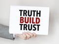 man's hand holding paper sheet with truth build trust words