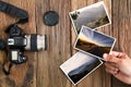 Man`s hand holding photo with old grunge camera and photos on vintage grunge wooden background Royalty Free Stock Photo